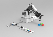Load image into Gallery viewer, A white and black robotic arm mounted on a base, shown with a control panel, joystick, small blocks, and a white box on a light gray studio background.