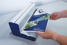 Load image into Gallery viewer, A Formax spiral-bound presentation binder being fed into a white and navy desktop printer or binding machine, with a person's hands guiding the printed booklet through the machine.