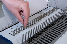 Load image into Gallery viewer, A close-up of a person's hand adjusting punch pins on a ReadyComb binding machine